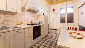 Una cocina con armarios blancos, salpicadero de azulejos, estufa y pileta.