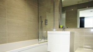 A bathroom with a bathtub, a toilet, and a shower area.