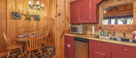 Un interior de madera con comedor, armarios rojos, un microondas y un lavavajillas.