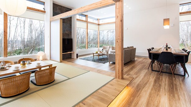 A modern interior with a dining area, a fireplace, and large windows offering a view of the outdoors.