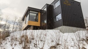 A modern building with a black exterior and a yellow accent wall, featuring large windows and a logo on the side.