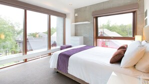 A modern bedroom with a large bed, a nightstand, a dresser, and a window offering a view of the outside. - Luxury 3 Bed Ski Chalet in Prime Location, Niseko Chalet 1001 (Niseko)