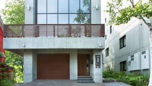 A modern building with a large garage door, a wooden balcony, and a sign indicating a business or office space. - Luxury 3 Bed Ski Chalet in Prime Location, Niseko Chalet 1001 (Niseko)