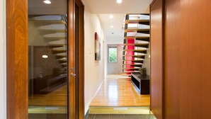 A modern interior with a wooden door, a glass wall, and a staircase with alternating red and black steps. - Luxury 3 Bed Ski Chalet in Prime Location, Niseko Chalet 1001 (Niseko)