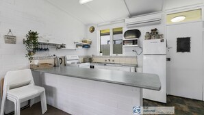 A kitchen with white appliances, a countertop, and a white chair.