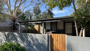 A residential property with a wooden gate, a brick wall, and a covered outdoor area.