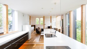 Eine moderne Küche mit einer langen Arbeitsplatte, einem eingebauten Herd und viel natürlichem Licht durch große Fenster.