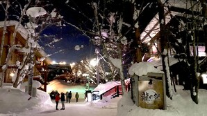 Lumipeitteinen ulkoalue, jossa on opastekyltti, polku ja taustalla näkyvä rakennus.