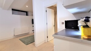 A modern kitchen with a built-in microwave, a small sink, and a yellow vase with flowers on the counter. - Spacious Double Room with en-suite - 1b (London)