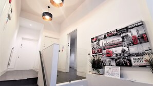 A hallway with a staircase, a wall-mounted light fixture, and a collage of photographs. - Spacious Double Room with en-suite - 1b (London)