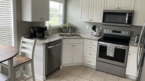 A modern kitchen with white cabinets, a built-in dishwasher, a stainless steel refrigerator, a microwave, an oven, and a sink. - Myrtle Beach Townhome on Legends Golf & Resort (Myrtle Beach)