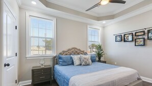 Quarto com cama grande, duas mesas de cabeceira, ventoinha no teto e janela com persianas.