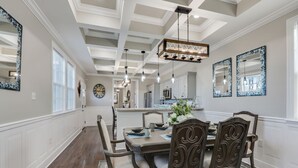 Uma sala de jantar com mesa de madeira, cadeiras e um lustre.