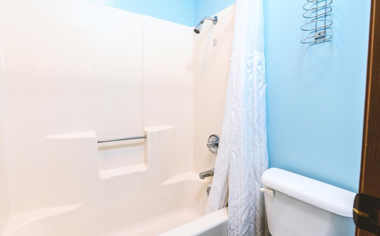 A bathroom with a shower, a toilet, and a towel rack.