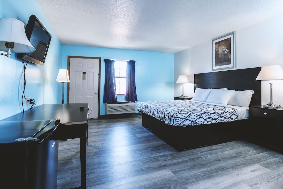A hotel room with a bed, desk, and television.