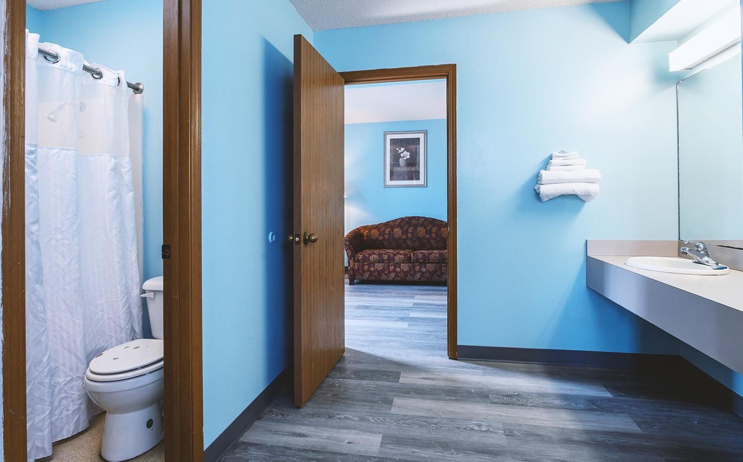 A bathroom with a toilet, shower curtain, and sink.
