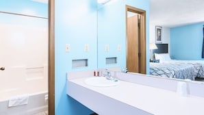 Un baño moderno con un espejo grande, lavamanos blanco y zona de ducha.