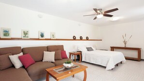 A modern living room with a sofa, a coffee table, a bed, and a ceiling fan.