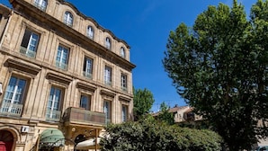 A historic building with multiple windows and balconies, surrounded by trees. - Hotel Le Relais De Poste (Arles)