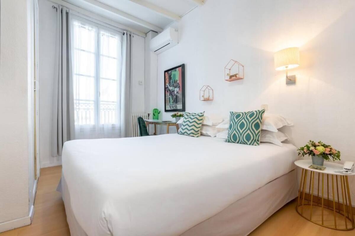 Ein Hotelzimmer mit einem großen Bett, einem kleinen Tisch mit Lampe und einer Wandleuchte.