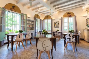A dining area with tables and chairs, a ceiling fan, and a view of the outdoors. - Hotel Le Relais De Poste (Arles)