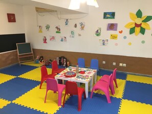 A children's playroom with colorful mats, a table with toys, and artwork on the walls. - Holiday Park (Varna)