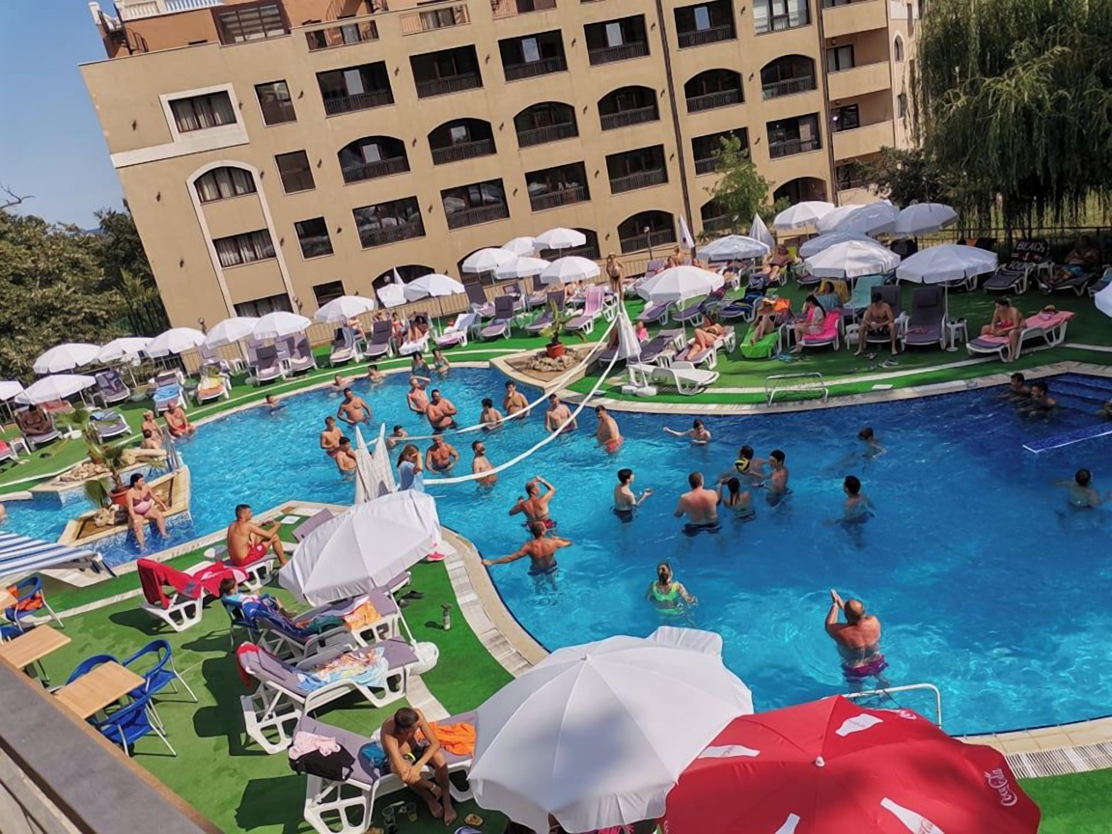 Zona de piscina con varios niveles de balcones, sillas de descanso y sombrillas.