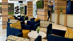 A modern lobby with seating areas, a reception desk, and a visible restaurant sign. - Holiday Park (Varna)