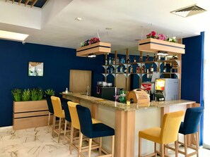 Un espace bar doté d’un comptoir en marbre, de tabourets de bar et d’une variété de bouteilles d’alcool.