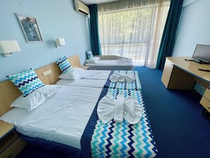 A hotel room with two beds, a desk, and a TV.