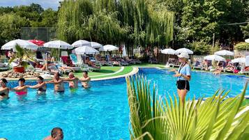 A swimming pool area with lounge chairs and umbrellas.