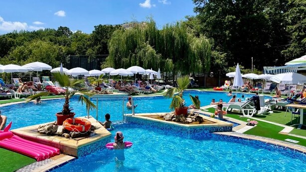A pool area with multiple sections, lounge chairs, umbrellas, and a small waterfall feature. - Holiday Park (Varna)