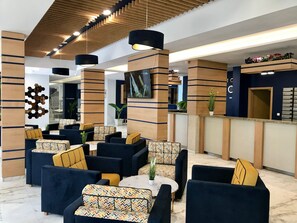 A modern lobby with sofas, a reception desk, and a wall-mounted clock. - Holiday Park (Varna)