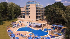A hotel with a swimming pool, multiple balconies, and outdoor seating areas. - Holiday Park (Varna)