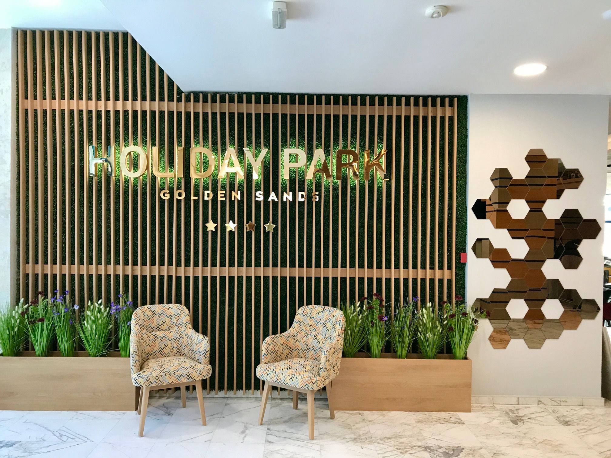 A reception area with a sign reading 'HOLIDAY PARK GOLDEN SANDS' and two patterned chairs in front.