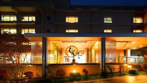 A modern hotel entrance with a glass facade, a visible reception area, and a landscaped garden. - Yorokobi no Yado Shinki (Shibukawa)