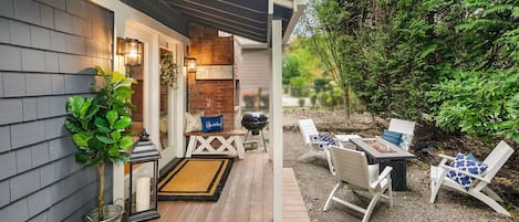 Een houten terras met buitenmeubilair, een barbecue en een bord met een welkomstbericht.