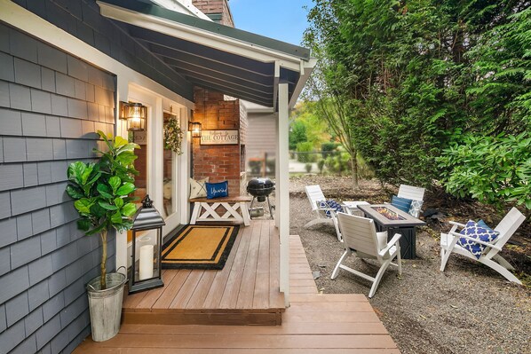 A wooden deck with outdoor furniture, a grill, and a welcome sign.