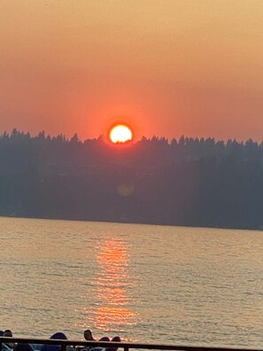 A sunset over a body of water with a forested shoreline.