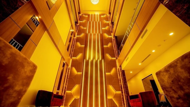 Eine moderne Hotelhalle mit einer zentralen Treppe, hohen Decken und zeitgenössischer Beleuchtung.