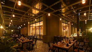 Ein Restaurant mit gedeckten Tischen, einem gemusterten Boden und hängenden Lampen.