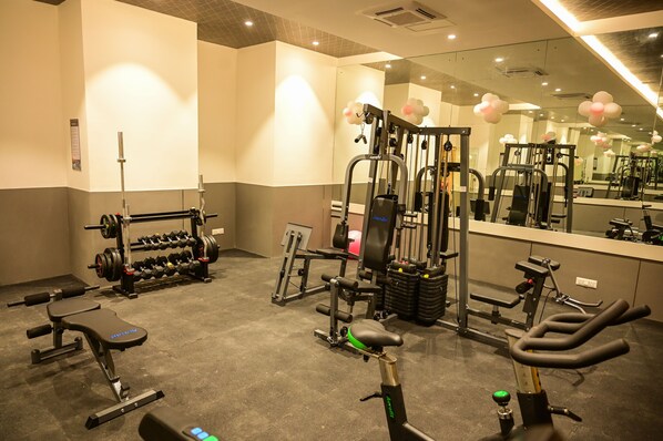 A gym with various exercise equipment, including dumbbells, a bench, and a stationary bike.