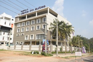 Un hotel con diseño moderno, varias plantas y entrada protegida, llamado Emerald Clark Inn Suites.
