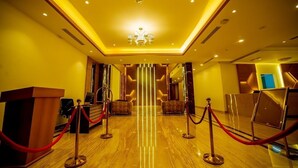 Eine Hotelhalle mit Empfangstresen, einer Chandelüster und einer roten Menschenmenge-Absperrung.