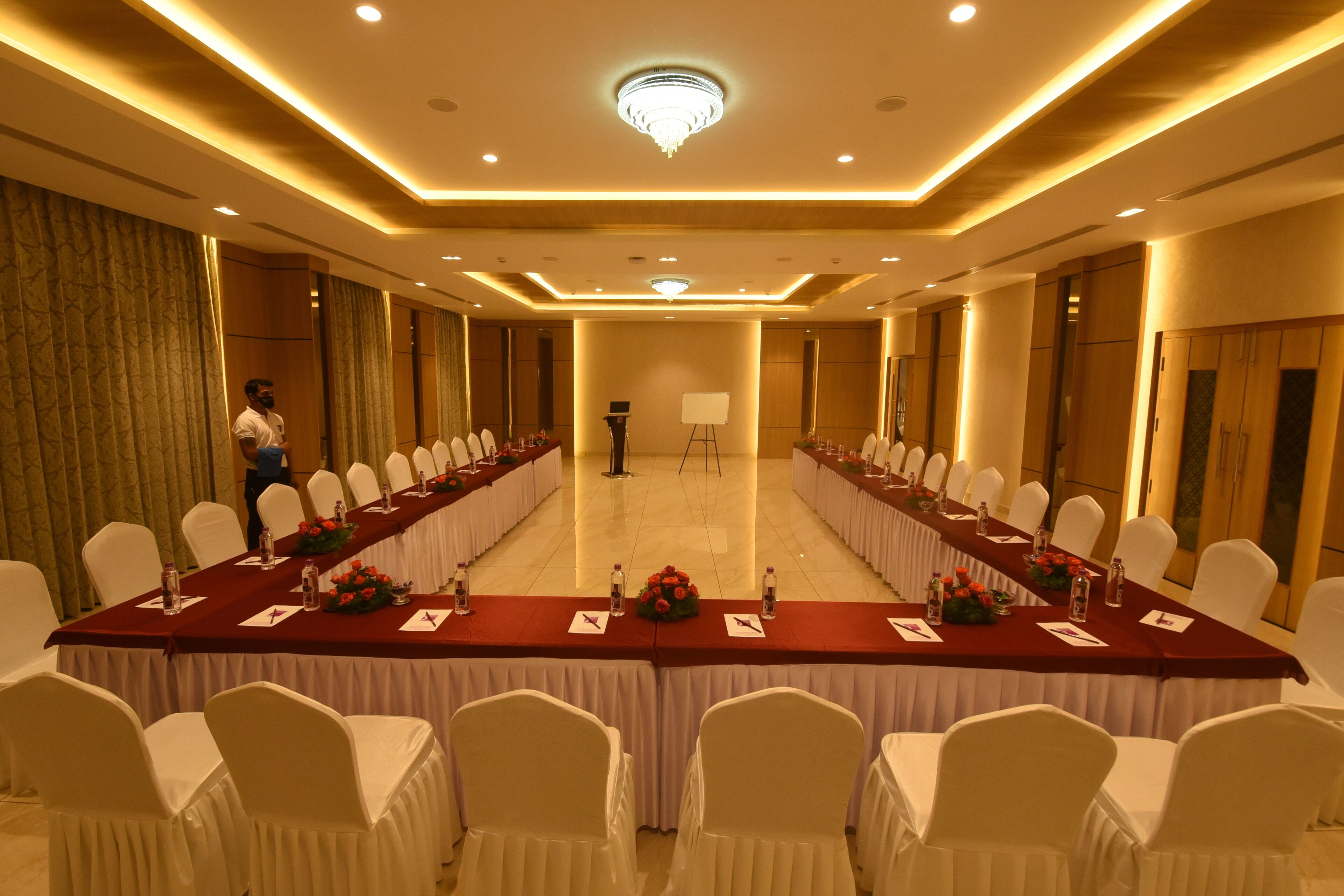 A conference room with a long table, white chairs, and a chandelier.