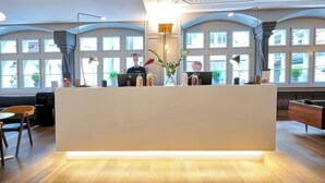 Un comptoir d’accueil au design moderne, de grandes fenêtres et un intérieur chaleureux.