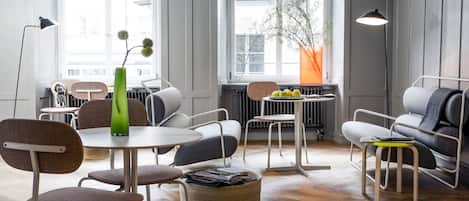 A modern living room with a round table, chairs, a sofa, and a radiator.
