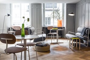 A modern living room with a round table, chairs, a sofa, and a radiator. - Marktgasse Hotel (Zürich)