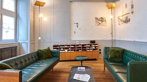 Une pièce spacieuse avec un canapé vert, un meuble en bois et une petite table.
