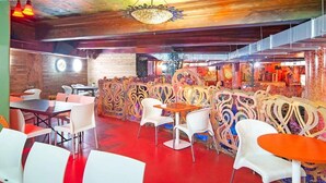 A restaurant with white chairs and tables, a red floor, and decorative wall art. - OYO Grand Central (Liverpool)